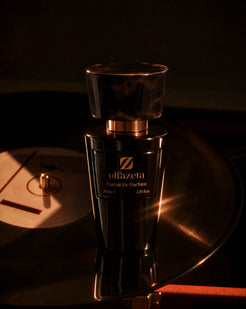 Black bottle Olfazeta by Chogan Millésime N°88 on a vinyl turntable, amber light on the record