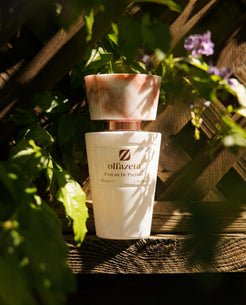 White bottle Olfazeta by Chogan Millésime N°53 on a wooden trellis, green foliage and mauve flowers